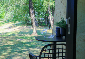 Tisch und Stuhl beim Solo Retreat in De Zanding, Niederlande, mit Blick auf grünen Garten und Bäume.