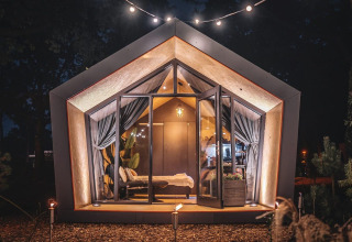 Ein modernes Solo Retreat-Lodge bei De Zanding in den Niederlanden, nachts gemütlich beleuchtet.
