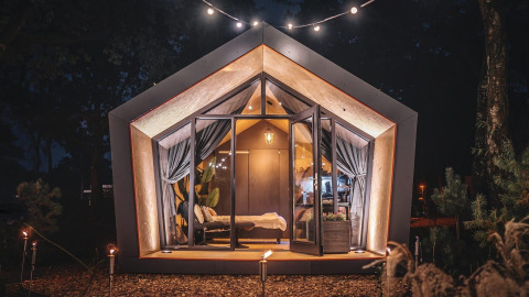 Et hyggeligt, moderne Solo retreat-lodge på De Zanding i Holland oplyst natten, omgivet af natur.