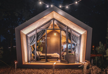 Acogedora y moderna cabaña Solo retreat en De Zanding, Países Bajos, iluminada por la noche en la naturaleza.