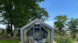Foto di un moderno lodge Solo Retreat con vetrata, tavolo da giardino e ambiente verde rigoglioso.