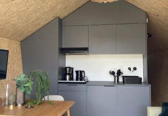 Moderna cucina e sala da pranzo nel lodge Solo Retreat di De Zanding, Paesi Bassi, con arredi in legno.