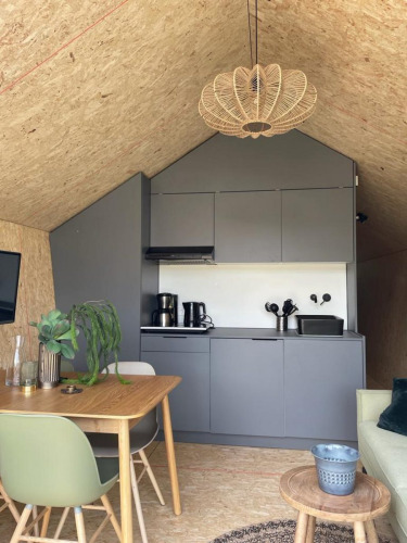 Modern compact kitchen and dining area in a Solo Retreat lodge at De Zanding, Netherlands, with wood decor.
