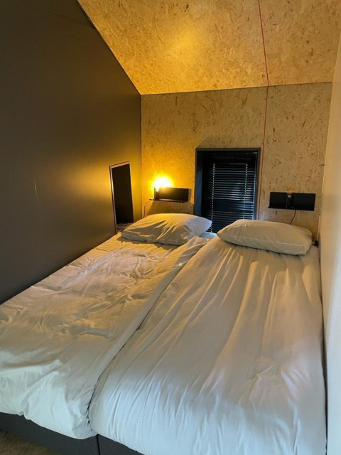 Dos camas individuales con sábanas blancas están juntas en una habitación moderna en Solo Retreat, De Zanding, Países Bajos.