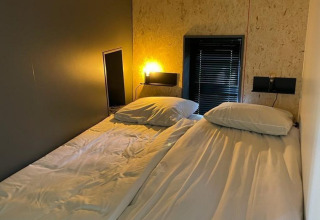 Dos camas individuales con sábanas blancas están juntas en una habitación moderna en Solo Retreat, De Zanding, Países Bajos.
