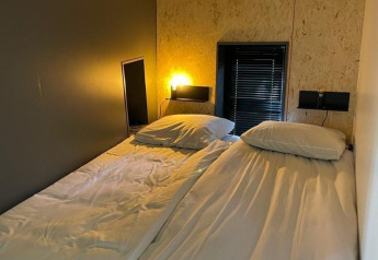 Dos camas individuales con sábanas blancas están juntas en una habitación moderna en Solo Retreat, De Zanding, Países Bajos.