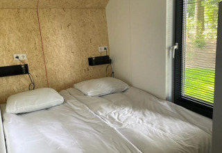 Moderne lodge met twee aparte bedden en groot raam bij Solo Retreat op De Zanding, Nederland.