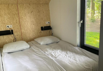 Camera moderna con due letti singoli e grande finestra al Solo Retreat a De Zanding, Paesi Bassi.