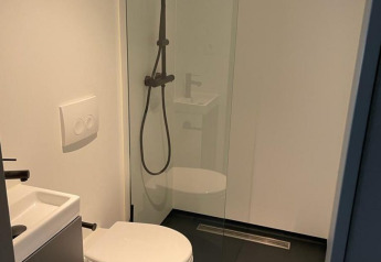 Bagno moderno al Solo Retreat, De Zanding, Paesi Bassi, con wc, piccolo lavandino e doccia a pioggia.