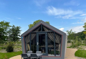 Solo Retreat lodge ved De Zanding i Holland, moderne bygning med terrasse, fire stole og grønne omgivelser.