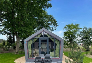 Moderna cabaña Solo Retreat en De Zanding, Países Bajos, con césped y árboles bajo un cielo despejado.