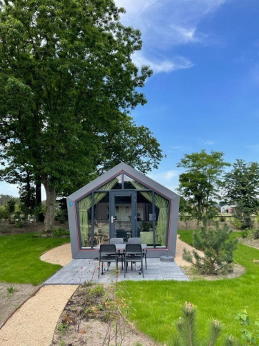 Modern Solo Retreat lodge at De Zanding in the Netherlands, surrounded by green grass, trees, and sky.