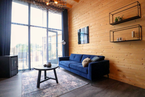 Soggiorno moderno nella Tiny House 2 al Marina Strandbad, Paesi Bassi, con divano blu e pareti in legno.
