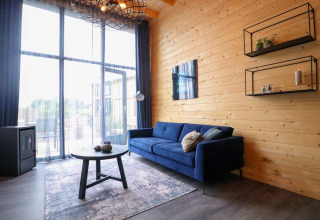 Moderne woonkamer in Tiny House 2 aan Marina Strandbad, Nederland, met blauwe zetel en houten muur.
