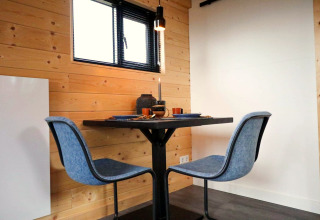 Zona pranzo con due sedie blu e un tavolino nel Tiny House 2 al Marina Strandbad, Paesi Bassi.