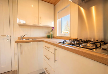 Cucina compatta e moderna in una sistemazione glamping con fornelli a gas, lavello e piano in legno.