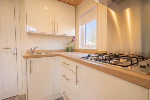 Cucina compatta e moderna in una sistemazione glamping con fornelli a gas, lavello e piano in legno.