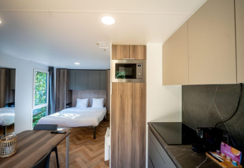 Moderna cabaña en Urban-Gardens Ieper, Bélgica con cama doble, cocina y mesa de comedor.