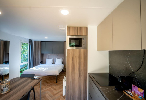Moderna cabaña en Urban-Gardens Ieper, Bélgica con cama doble, cocina y mesa de comedor.