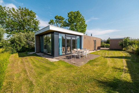 Lodge moderno Pavilion con ventanales y terraza exterior en Poort van Zeeland, Países Bajos, día soleado.