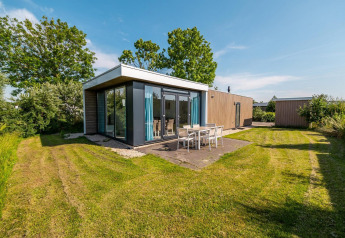 Lodge moderno Pavilion con ventanales y terraza exterior en Poort van Zeeland, Países Bajos, día soleado.