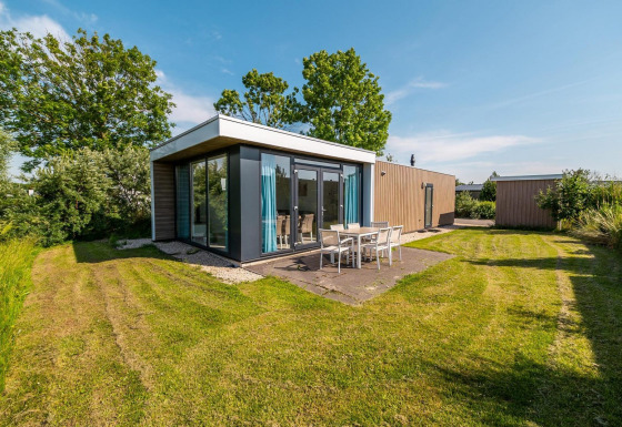 Lodge Pavilion moderno con grandi vetrate e terrazza a Poort van Zeeland nei Paesi Bassi, in ambiente verde.