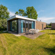 Moderne pavillon-lodge med glasfacader og udendørs spisebord på græsplæne i Poort van Zeeland, Holland.