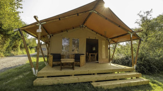 Safari tent called Comet 27 Lodges with a wooden deck, two chairs, and a table in front of the entrance.