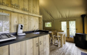 Interior de tienda safari con cocina y muebles de madera en Comet 27 Lodges, Arden Parks, Signy l'Abbaye, Francia.