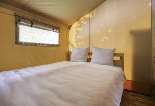 Vista interior de una tienda safari con cama doble en Comet 27 Lodges en Arden Parks, Signy l'Abbaye, Francia.