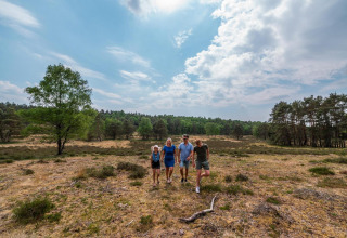 Una familia disfruta de un paseo por la naturaleza cerca de su alojamiento glamping bajo un cielo nublado.