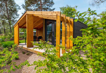 Tiny house Panorama Cottage avec terrasse en bois, entourée de verdure et d’arbres en pleine nature.