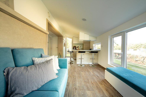 Interno luminoso mini casa a Panorama Cottage, De Hooge Veluwe, Paesi Bassi, divano blu e cucina moderna.