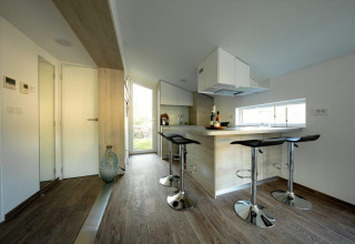 Cucina moderna e compatta con zona pranzo e sgabelli a Panorama Cottage, De Hooge Veluwe, Paesi Bassi.