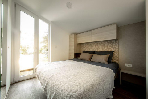 Dormitorio moderno con cama doble y ventanas grandes en Panorama Cottage, De Hooge Veluwe, Países Bajos.
