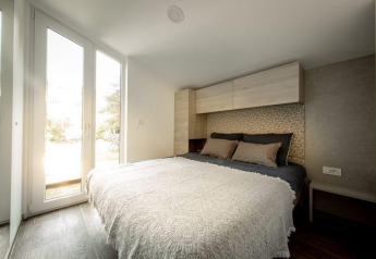 Camera da letto moderna con letto matrimoniale e grandi finestre al Panorama Cottage, De Hooge Veluwe, Paesi Bassi.