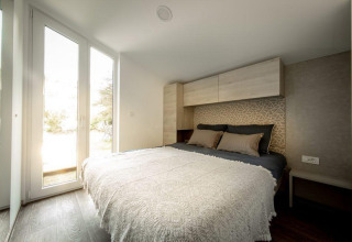 Camera da letto moderna con letto matrimoniale e grandi finestre al Panorama Cottage, De Hooge Veluwe, Paesi Bassi.