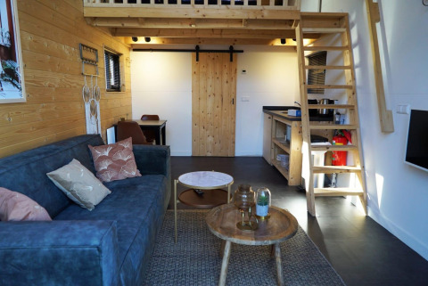 Interior de tiny house en De Hooge Veluwe, Países Bajos, con entrepiso, sofá y decoración de madera.