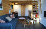 Interior de tiny house en De Hooge Veluwe, Países Bajos, con entrepiso, sofá y decoración de madera.
