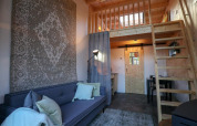 Vista interior de la Tiny House en De Hooge Veluwe, Países Bajos, con loft, sofá y decoración de madera.