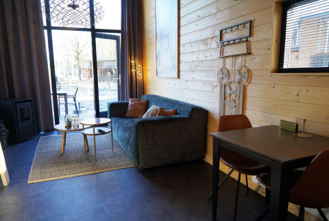 Hyggelig stue i en Tiny House ved De Hooge Veluwe i Holland med sofa, bord og store vinduer.