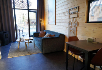 Acogedora sala en una Tiny House en De Hooge Veluwe, Países Bajos, con sofá, mesa y grandes ventanas.