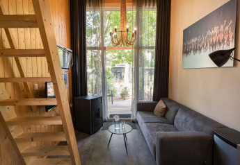 Stijlvol interieur van een Tiny House-lodge op De Hooge Veluwe in Nederland, met bank, hout en grote ramen.
