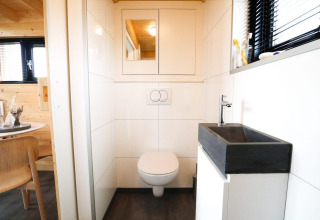 Moderne badeværelse med væghængt toilet og sort håndvask i et Tiny House på De Hooge Veluwe i Holland.