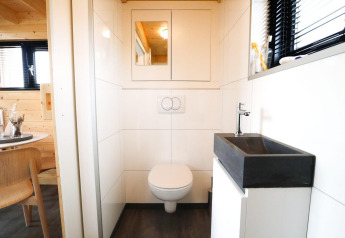 Moderne badeværelse med væghængt toilet og sort håndvask i et Tiny House på De Hooge Veluwe i Holland.