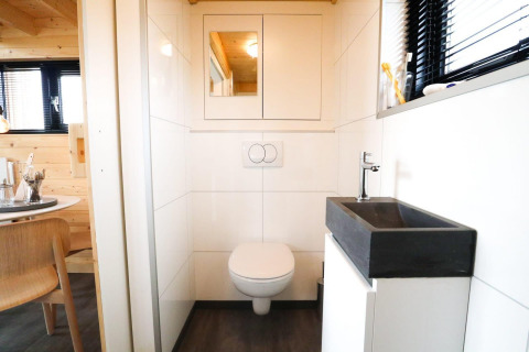 Moderne badeværelse med væghængt toilet og sort håndvask i et Tiny House på De Hooge Veluwe i Holland.