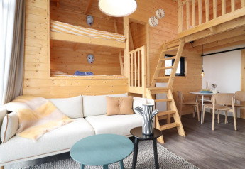 Moderne, hyggelig træinteriør af Tiny House på De Hooge Veluwe i Holland med køjesenge og stue.