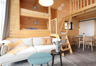Moderne, hyggelig træinteriør af Tiny House på De Hooge Veluwe i Holland med køjesenge og stue.