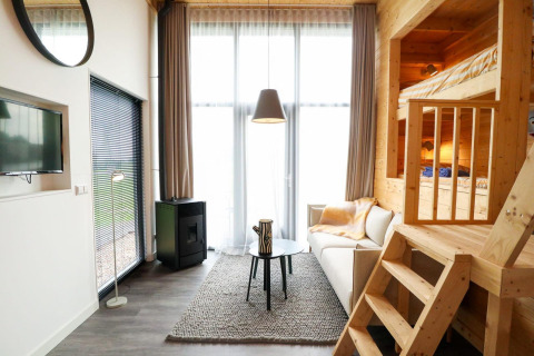 Moderne Tiny House lodge med hems, store vinduer og komfortabel sofa på De Hooge Veluwe, Holland.