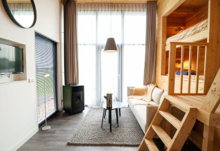 Moderne Tiny House lodge med hems, store vinduer og komfortabel sofa på De Hooge Veluwe, Holland.